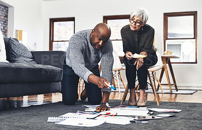 Buy stock photo Full length shot of two businesspeople looking over paperwork while working on the floor of their office