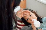 Little girl, fever and hand of mom in house, milk and bottle for cute toddler to drink. Mother, check and touch head of child for sickness in youth, kid and daughter with mama as family in home