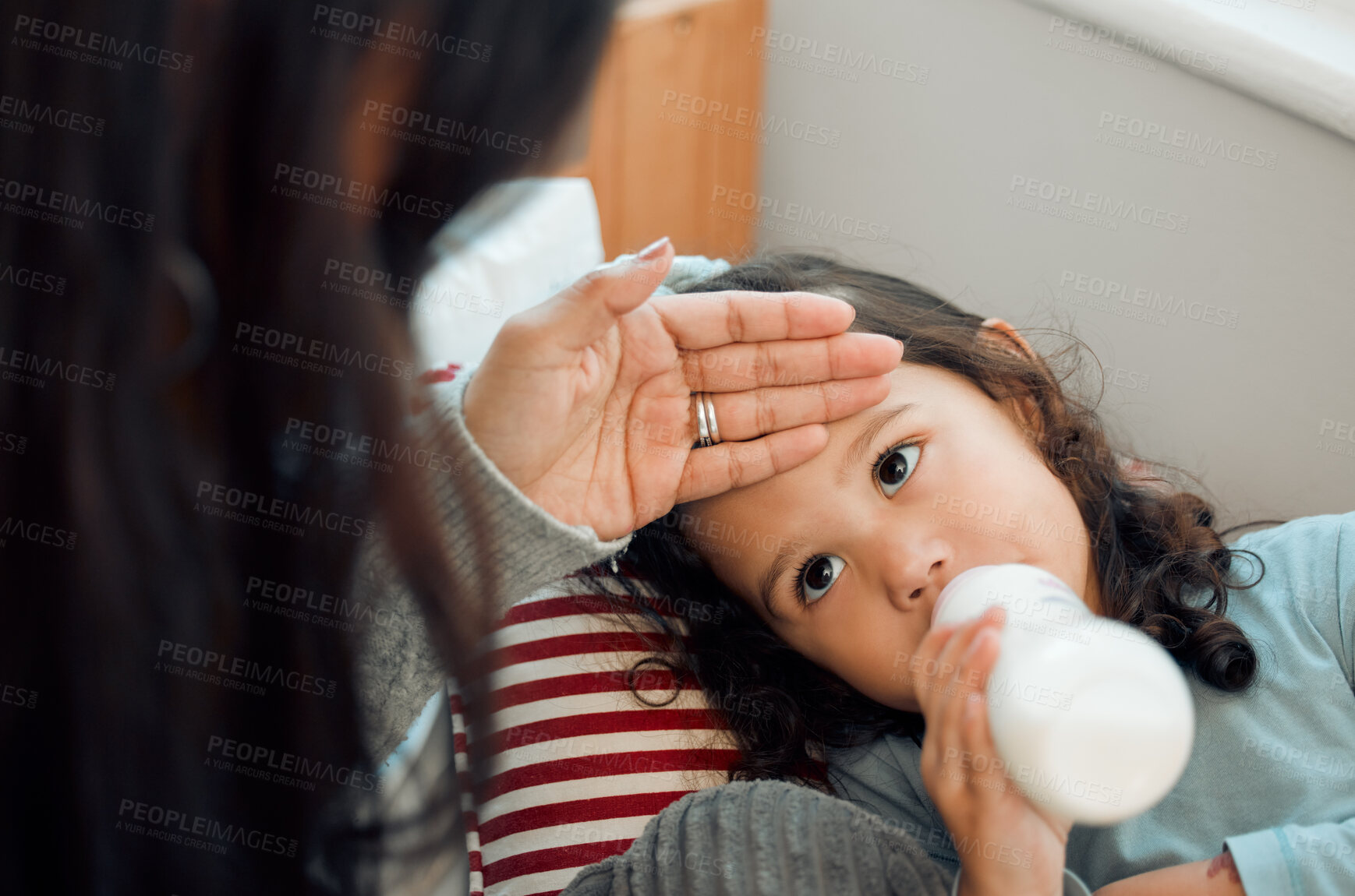 Buy stock photo Little girl, fever and hand of mom in house, milk and bottle for cute toddler to drink. Mother, check and touch head of child for sickness in youth, kid and daughter with mama as family in home