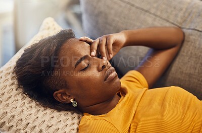 Tired, bored and exhausted female sleeping on a couch at home and holding her head. African female relaxing and resting on a sofa due to headache or migraine in her house. Lady lying down closed eyes