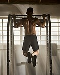 Strong, fitness and active man doing bodybuilding, strength and muscle full body workout with gym equipment. Rear of a fit trainer training or exercising to tone body for muscular or masculine figure