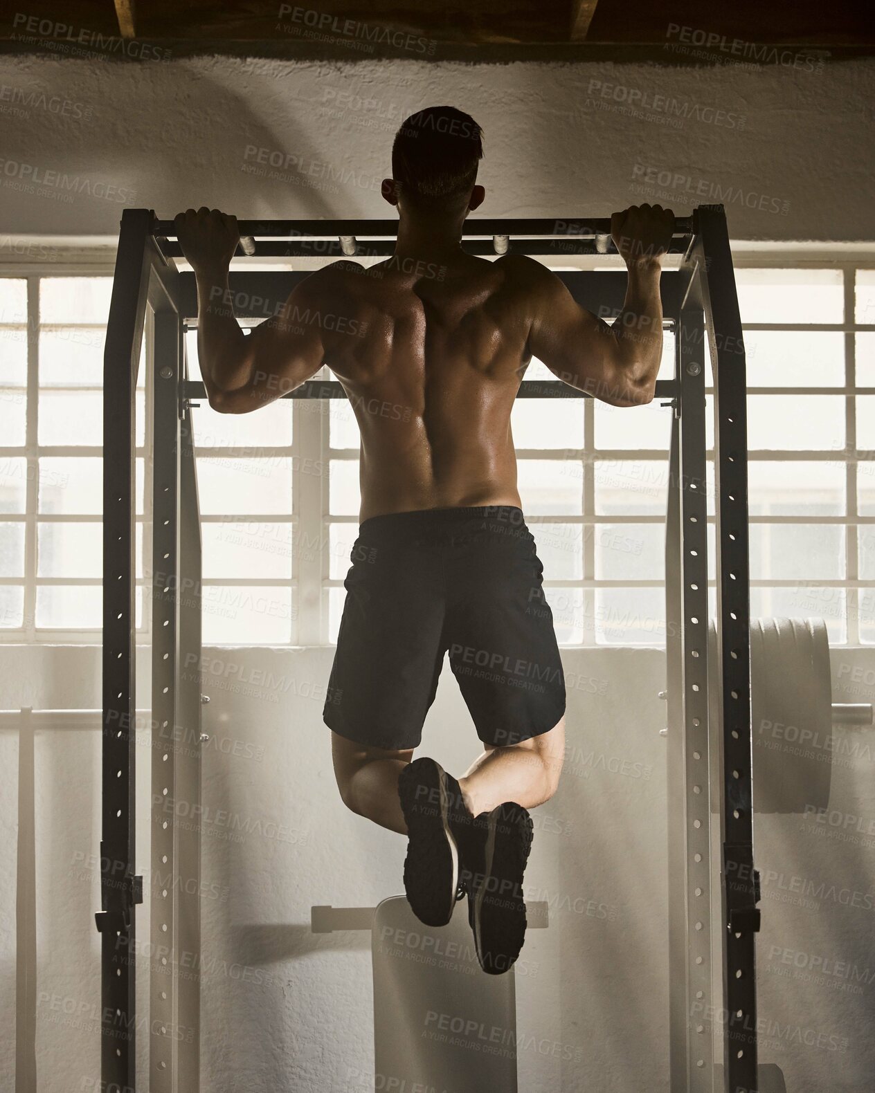 Buy stock photo Strong, fitness and active man doing pull up strength and muscle full body workout with gym equipment. Rear of a fit trainer in an endurance bodybuilding or training exercise for a muscular figure