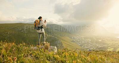 Woman, hiking and video recording on mountains in adventure, wellness and health with nature and cityscape. Person with backpack and trekking photography on green hill, travel or eco friendly journey