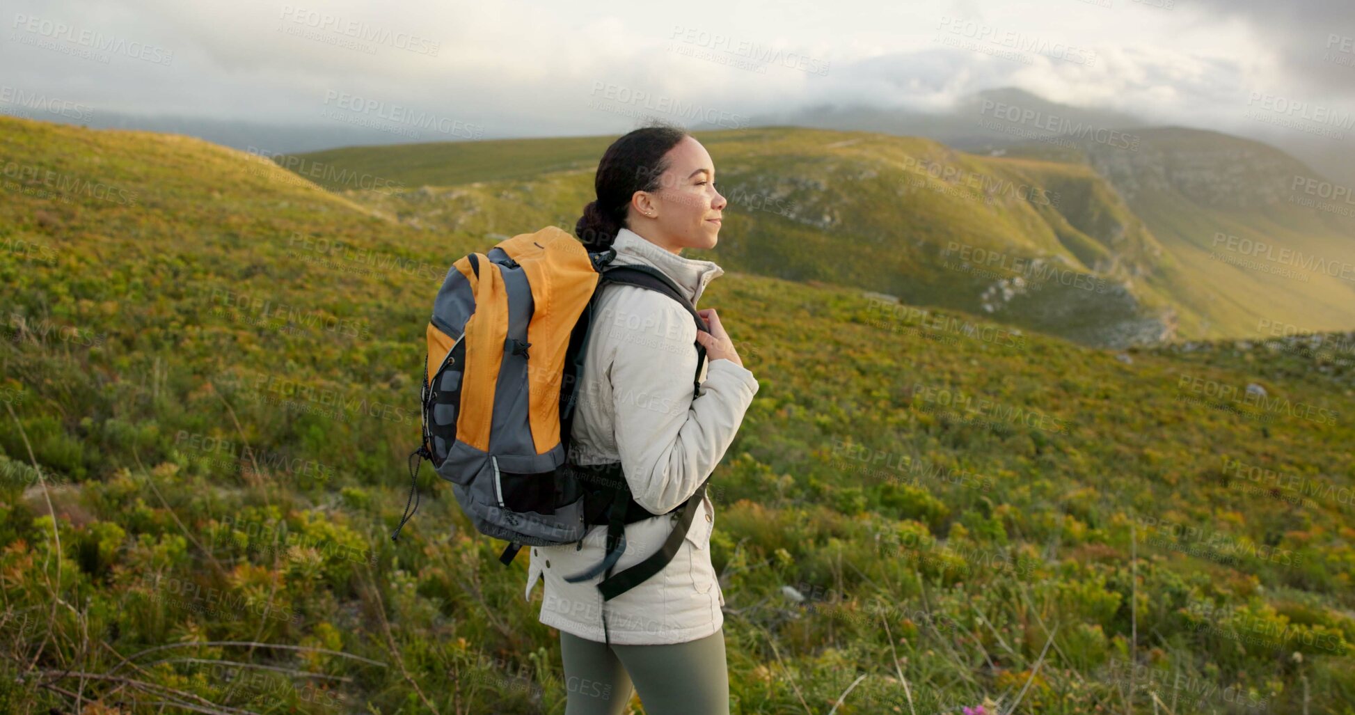 Buy stock photo Woman, hiking on mountains and breathing fresh air for outdoor wellness, fitness and health in nature. Happy young person in wind with backpack and trekking on a hill for adventure, travel or journey
