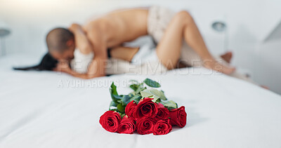 Couple, red roses and lying on bed for love, anniversary or valentines day in romance, embrace or trust at home. Romantic man and woman in bedroom intimacy, passion or bonding with flowers at house