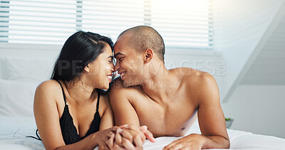 Happy couple, relax and kissing on bed for intimacy, morning romance or love in embrace, trust or care at home. Young man and woman smile lying in bedroom for passion or bonding together at house