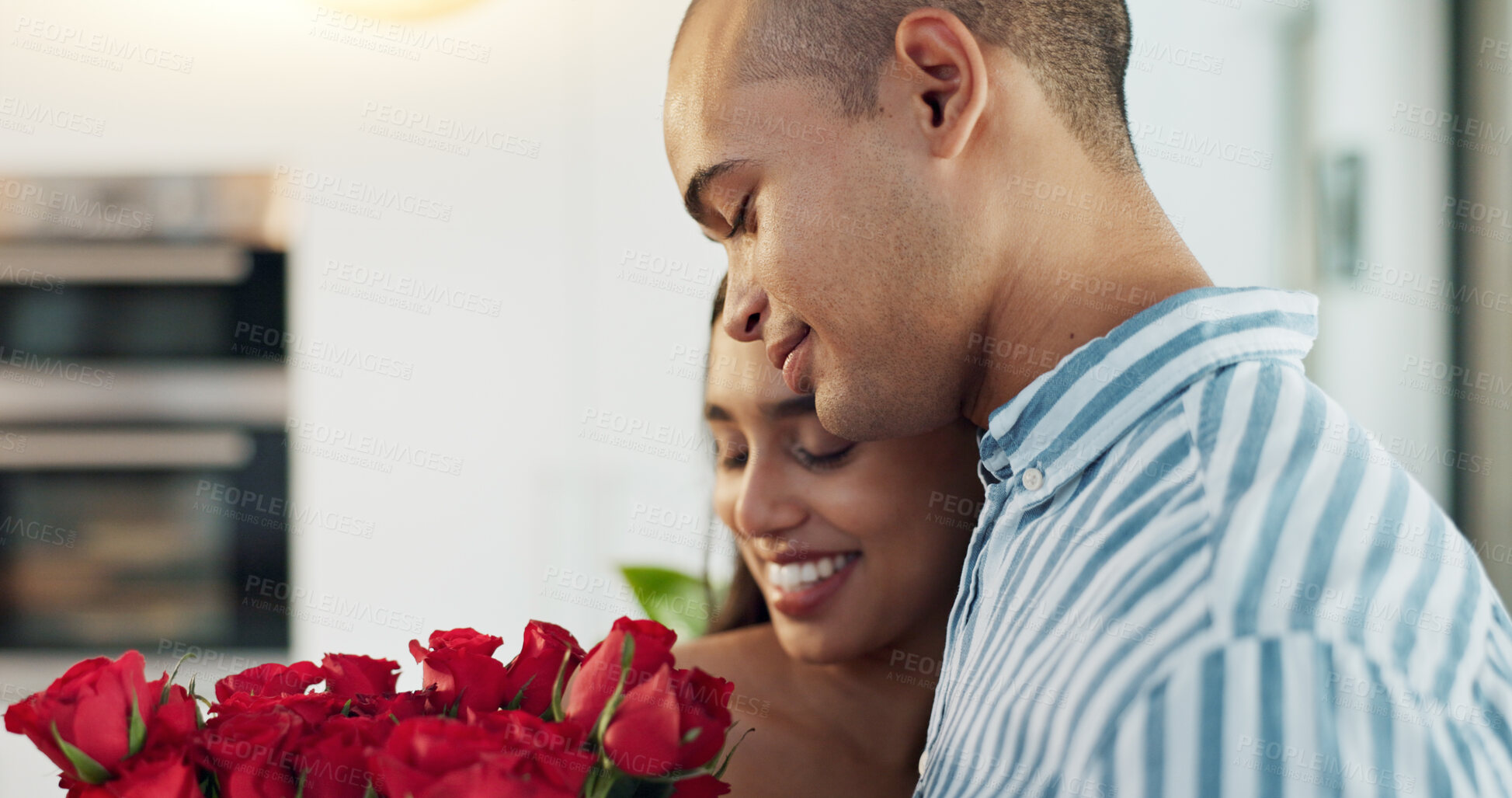 Buy stock photo Happy couple, red roses and kiss for surprise, anniversary or valentines day in kitchen at home. Face of young man and woman smile with flowers for romantic gift, love or care in celebration at house