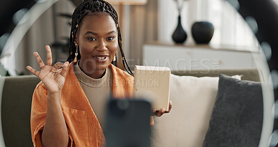 Wave, live streaming and happy black woman with box or product in home living room. Hello, influencer and person with package, record video on social media and content creation, ring light and phone
