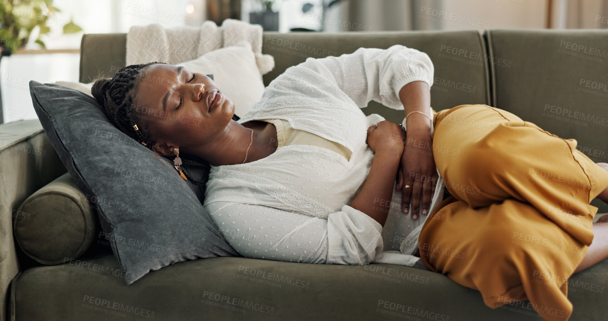 Buy stock photo Home, pain and black woman on a couch, cramps and stomach with sickness, suffering and disease in the living room. African person, apartment and girl with abdominal problem, tummy ache and period