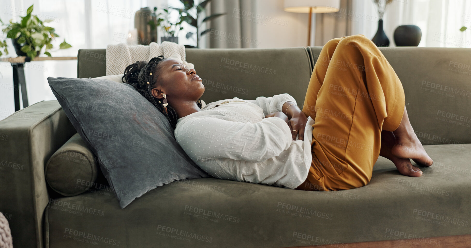 Buy stock photo Home, pain and black woman on a couch, cramps and stomach with sickness, suffering and disease in the living room. African person, apartment and girl with abdominal problem, tummy ache and period