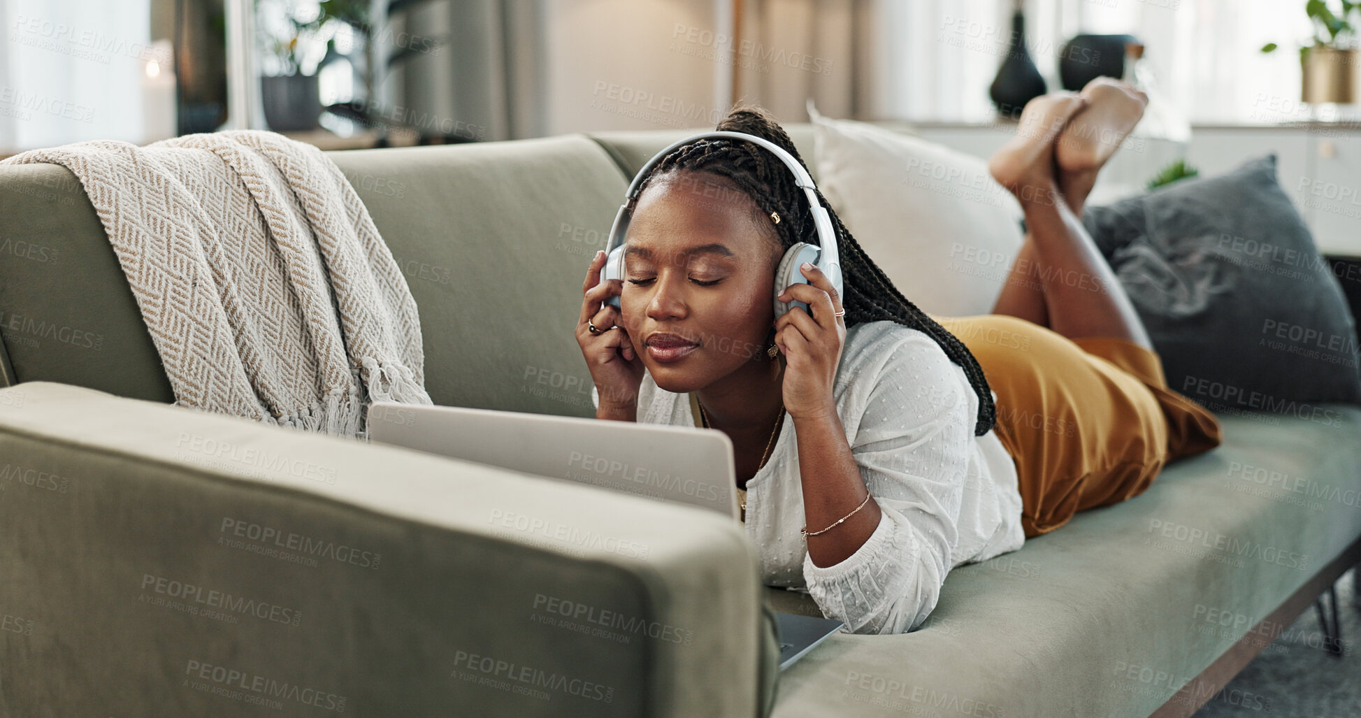 Buy stock photo Home, headphones and black woman on a couch, laptop and typing with connection, internet and streaming music. African person, apartment and girl on a sofa, pc and headset with sound, song and audio