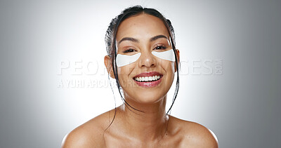 Face, eye patches and woman with skincare, cosmetics and dermatology on a grey studio background. Portrait, person and model with beauty, treatment and healthy skin with grooming, smooth and shine