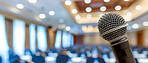Microphone, public speaking and conference setup in an empty hall for event planning, convention and workshop. Closeup, banner and equipment for corporate business, marketing strategy or announcement