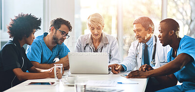 Buy stock photo Shot of a team of doctors using a laptop together during a meeting