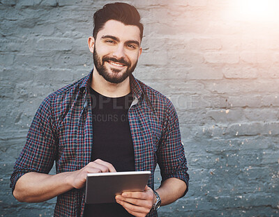 Buy stock photo Portrait of a young man standing outdoors and using a digital tablet against a gray wall