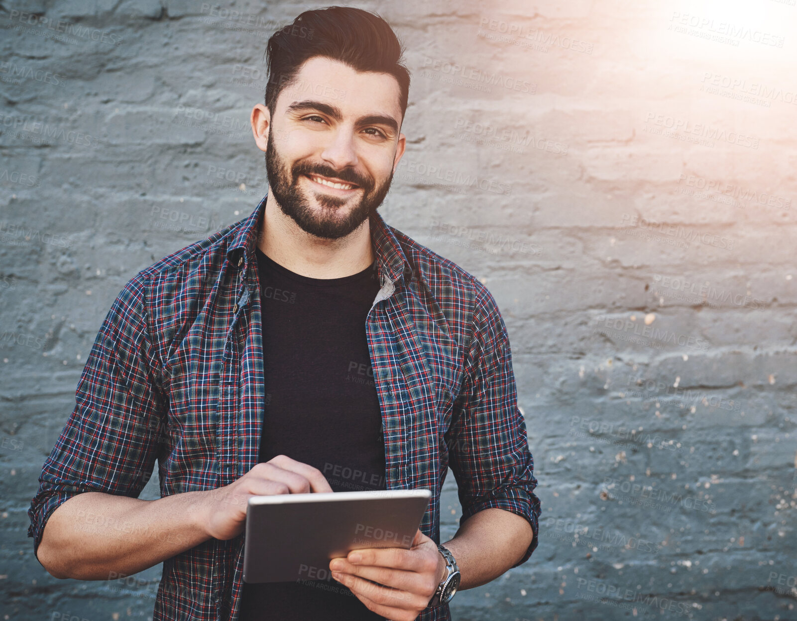 Buy stock photo Portrait of a young man standing outdoors and using a digital tablet against a gray wall