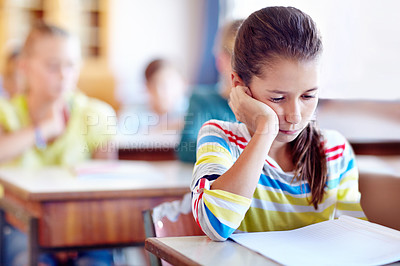 Buy stock photo Child, school and desk with book or bored in classroom or education lesson or reading, knowledge or studying. Girl, kids and unhappy or learning or tired pupil with paper or fatigue, student or moody