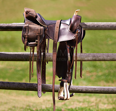 Buy stock photo Saddle, horse and farm on ranch fence, riding and equestrian sports in country side. Western, cowboys and field in Texas, stirrup and leather seat or equipment for outdoors exercise in paddock