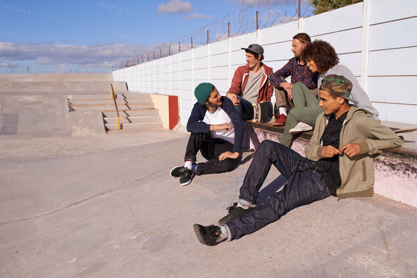 Buy stock photo Skate park, diversity and friends with conversation, sunshine and relaxing with discussion and happiness. Multiracial, gen z and team on a break, summer and bonding together with skaters and group