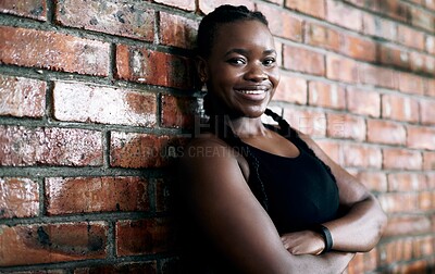 Buy stock photo Cropped portrait of an attractive young female athlete standing with her arms crossed against a brick wall in the gym