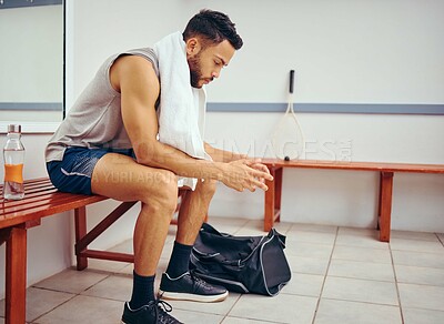 Buy stock photo Serious young player sitting in a locker room. Mixed race man waiting in a gym locker room. Young man taking a break from his match, thinking in the gym. Focused man in the gym