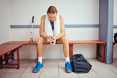Buy stock photo Young squash player sitting in a locker room waiting for his match. Caucasian player taking a break and thinking in his gym. Squash player sitting with his racket and bag before a match.