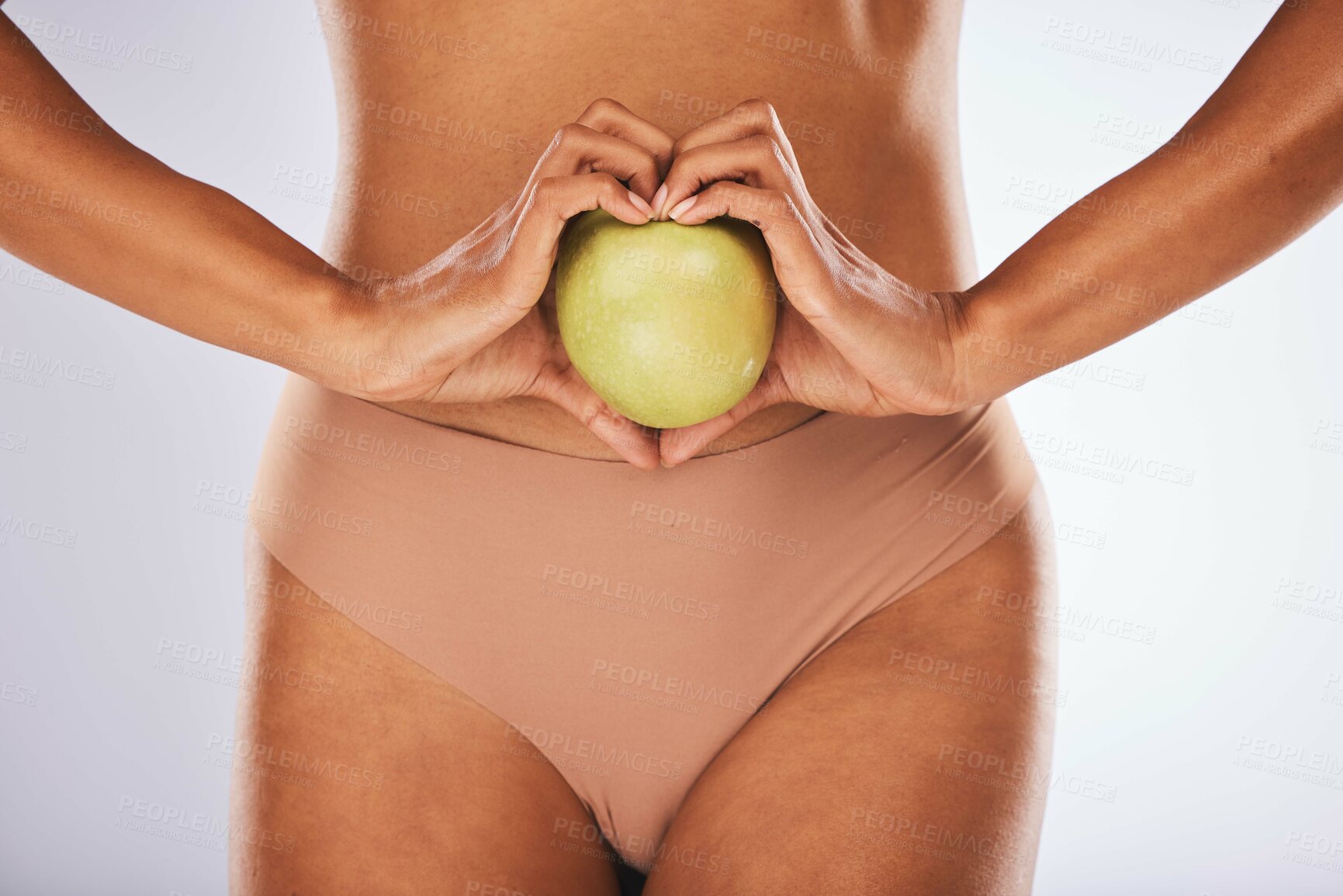 Buy stock photo Health, heart shape and woman with a apple for a healthy, nutrition and organic diet snack. Fitness, wellness and slim female body with love hand gesture for fruit for weightloss by studio background