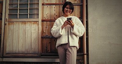 Buy stock photo Japanese woman, phone and texting in city, thinking and reading for communication, notification or app. Girl, person and smartphone with mobile network, social media and smile on metro road in Tokyo