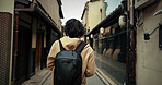 Travel, man and backpack in Japan with vacation, adventure and holiday with back outdoor in city. Urban road, journey and person walking in town with Japanese architecture Hanamikoji Street of Kyoto