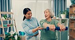 Senior care, physiotherapy and caregiver with old woman, dumbbell and healthcare at nursing home. Physio, exercise and retirement, fitness coach and elderly patient with mobility training in office.