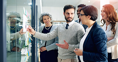 Buy stock photo Shot of a group of businesspeople brainstorming on a glass wall in an office