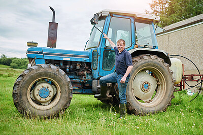 Buy stock photo Portrait of a cheerful young farmer posing next to his large farm tractor outside on a field