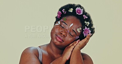 Face, flowers and beauty with a body positive black woman in studio on a gray background for natural wellness. Portrait, skincare and a confident young plus size model feeling her aesthetic skin