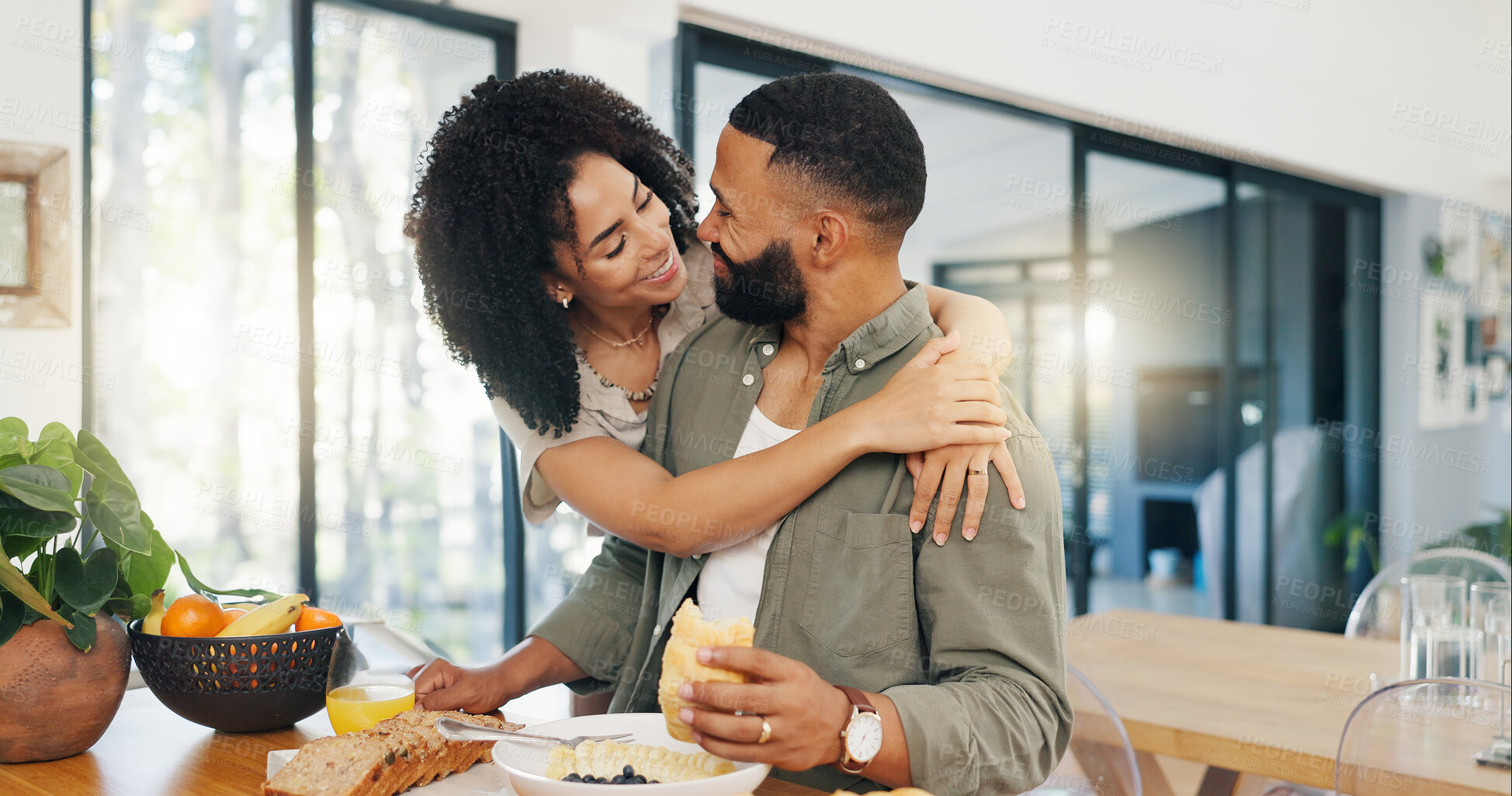 Buy stock photo Happy couple, surprise and breakfast at table with hug, talking and bonding together in morning with love. Man, woman and eating healthy food on kitchen counter, embrace and care in marriage in home