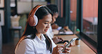 Woman, headphones and cafe with smartphone, streaming music and singing in shop, texting and social media. Happy, young and technology for podcast, listening and networking on subscription app