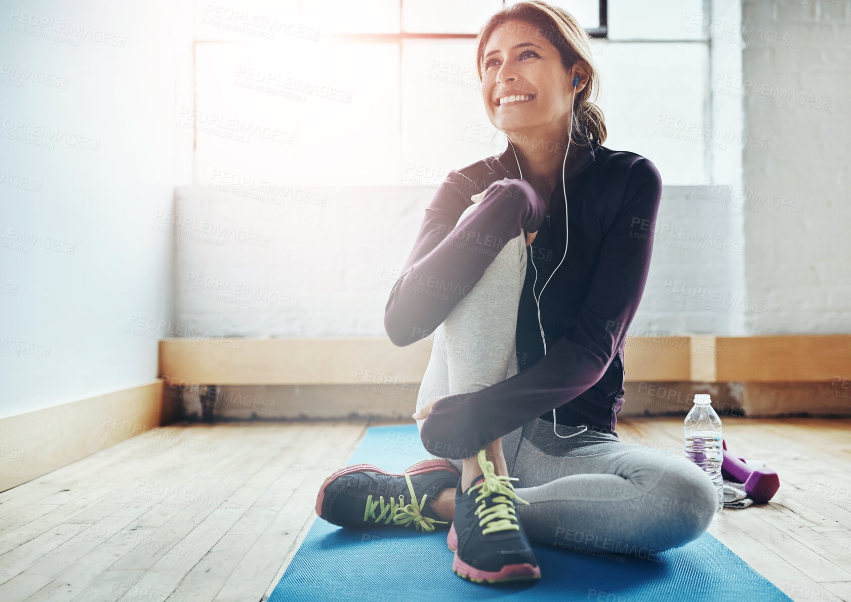 Buy stock photo Happy woman, fitness and mat in gym with earphones, relax and ready for workout with water. Smile, female person and music for exercise with hydration, funny podcast and audio book in subscription