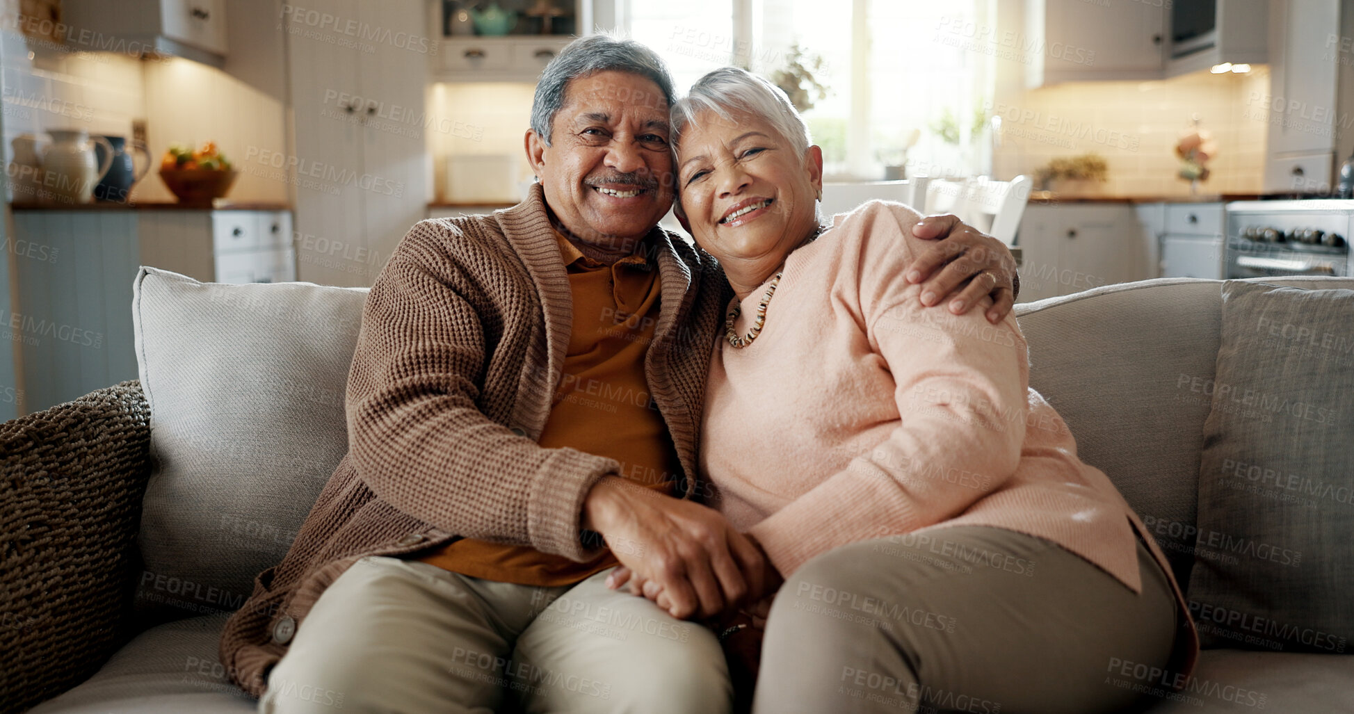 Buy stock photo Senior couple, face and hug on couch, smile and bonding with love, support and relax in retirement in home. Elderly woman, old man and portrait with embrace, together and sitting on living room sofa