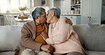 Happy, senior couple and a kiss on the sofa for love, relax and a hug in a house. Together, smile and an elderly man and woman with care, comfort and romance in a marriage on the living room couch