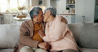 Happy, senior couple and a kiss on the sofa for love, relax and a hug in a house. Together, smile and an elderly man and woman with care, comfort and romance in a marriage on the living room couch