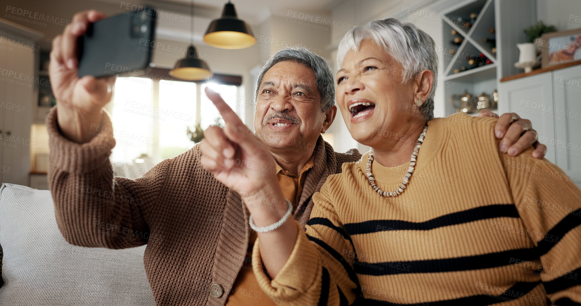 Buy stock photo Senior couple, selfie and happy on sofa, hug or talking for choice, check post and point for photography in home. Elderly woman, man and laugh with profile profile, web blog and social media on couch