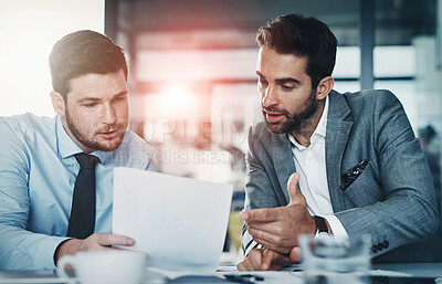 Buy stock photo Shot of two young businessmen going through paperwork together in a modern office