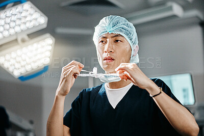 Medical, uniform and doctor in theatre for surgery, safety and preparation for operation in hospital. Asian man, surgeon and clothes with thinking for cardiology procedure, protection and healthcare