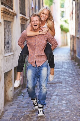 Buy stock photo Couple, happy or piggyback on street in city, fun support or romance in committed relationship. Excited man, woman and smile for adventure in amsterdam, travel and care for love together on honeymoon