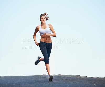 Buy stock photo Shot of a sporty young woman enjoying a run outdoors