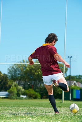 Buy stock photo Back, kick and man playing with rugby ball on a grass field to score during workout. Athlete, sport and professional player training for healthy workout in a uniform for kicking exercise with energy