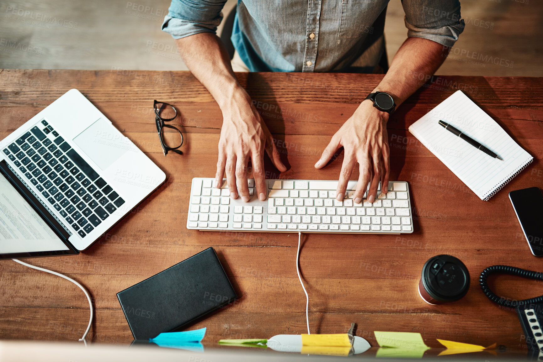 Buy stock photo Cropped high angle shot of a businessman using a computer at his desk in a modern office