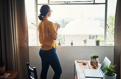 Buy stock photo Cropped shot of an attractive young businesswoman standing in her home office and looking contemplative while holding a coffee cup