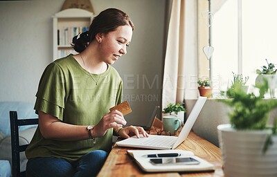 Buy stock photo Cropped shot of an attractive young businesswoman sitting alone in her home office and using her laptop for online shopping