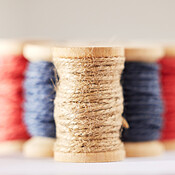Many rolls of coloured yarn or string lined up in a row in studio ...