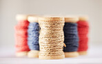 Many rolls of coloured yarn or string lined up in a row in studio isolated against a grey background. For the production of textiles, sewing, crocheting, knitting, weaving, embroidery or rope making